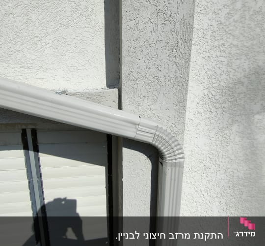 צינור מרזב אפור מחובר לקיר חיצוני